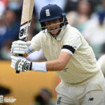 Joe Root, in white shirt and blue cap, in action