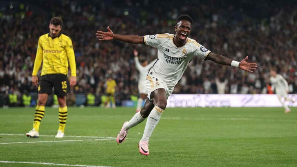 Vinicius Junior raising both arms while running off the pitch