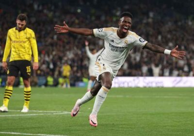 Vinicius Junior raising both arms while running off the pitch