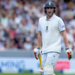 Harry Brook, in white uniform and dark cap, looks on during a match break. Brook has been tapped as England captain, replacing Joe Buttler