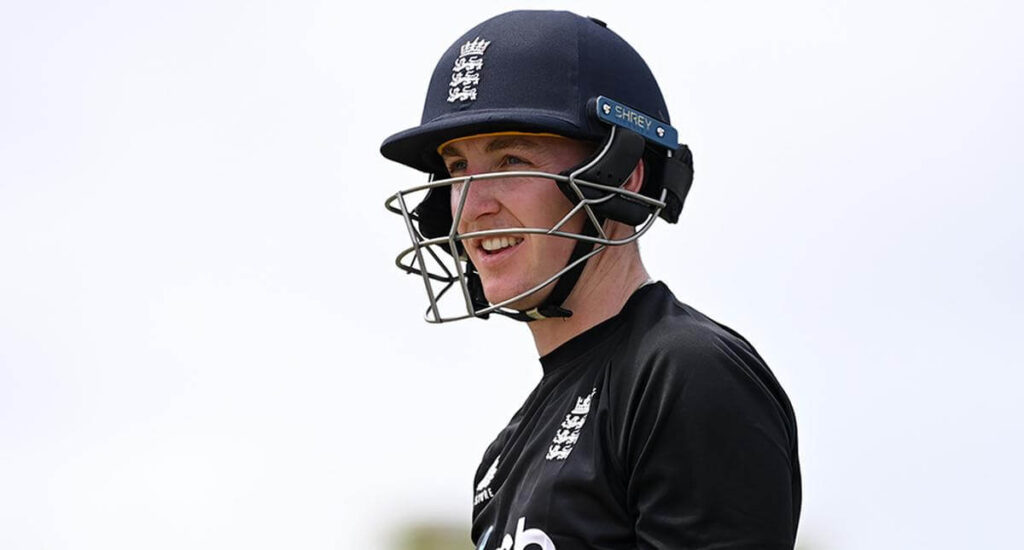 Harry Brook, in black uniform and helmet, surveys the field during a match break. Brook has been tapped to replace the injured Joe Buttler as England captain.