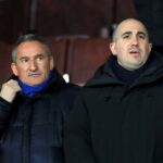 Man United CEO Omar Berrada, right, in black coat and shirt, watches a match.