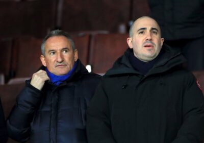 Man United CEO Omar Berrada, right, in black coat and shirt, watches a match.