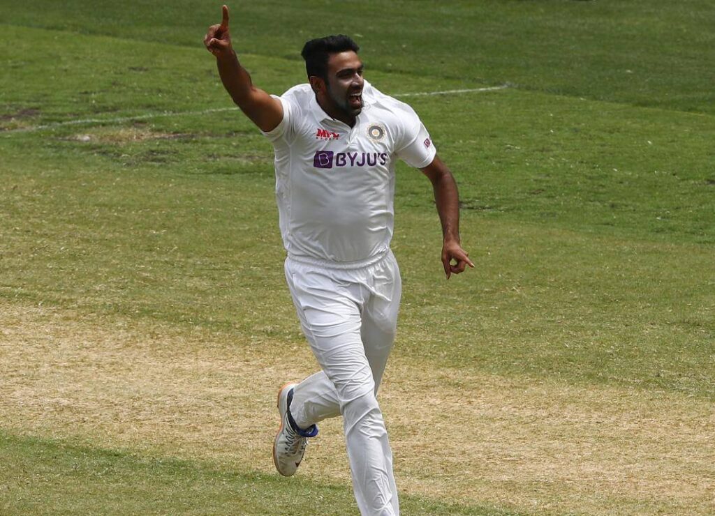 Muttiah Muralitharan, in white uniform, raises his finger in celebration during a match. Muralitharan doubts if his Test wickets record can be broken