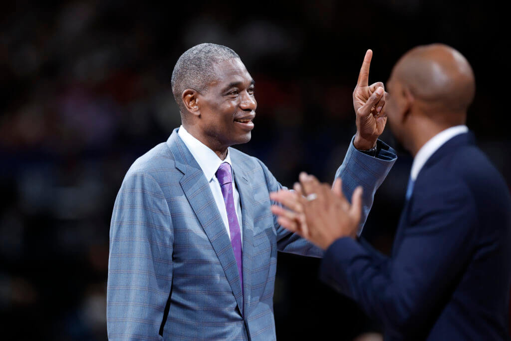 Dikember Mutombo, in gray suit, displays his "finger wagging move" at a recent event. The NBA world mourns after Mutombo passed away on Monday.,