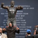 Retired Miami Heat legend Dwyane Wade, in black suit, mimics the pose of his new statue outside the Heat's team arena on Sunday. Wade explains new statue look, cites 'artistic version' of a moment