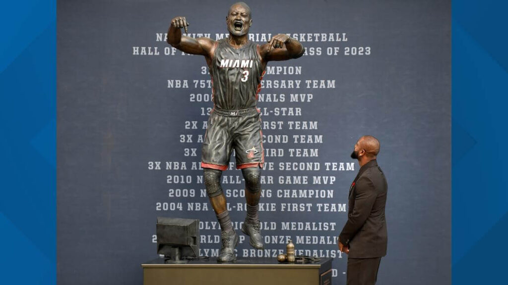 Retired Het legend Dwyane Wade, in black suit, looks on his new statue on Sunday. Wade explains new statue look, cites 'artistic version' of a moment