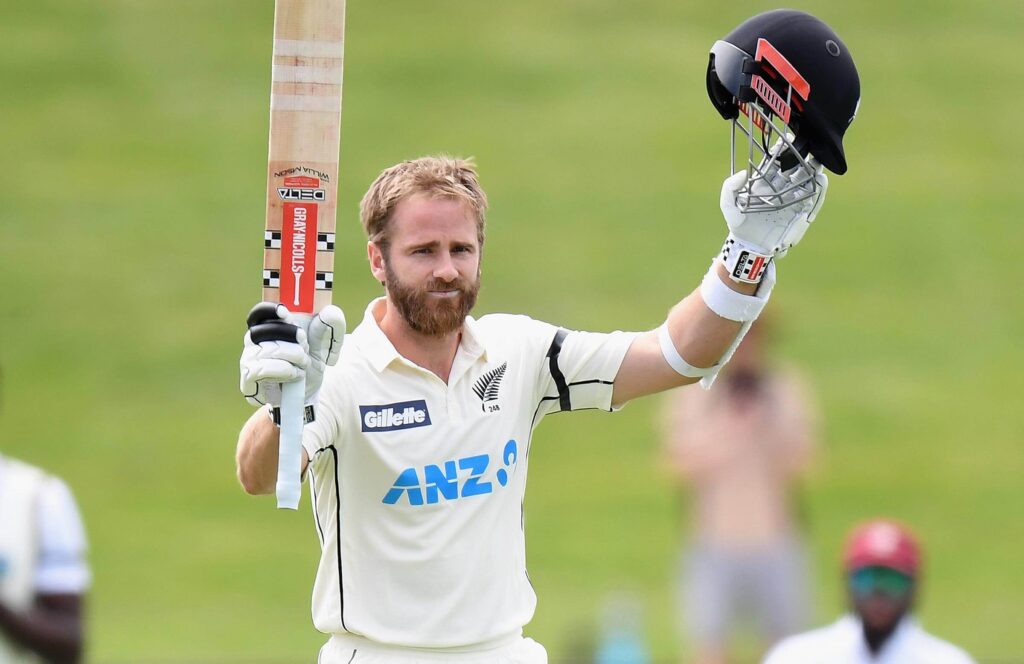 Kane Williamson, in white uniform, gestures during a match break.  Expect New Zealand to miss Williamson in the first Test series against India due to a groin strain.