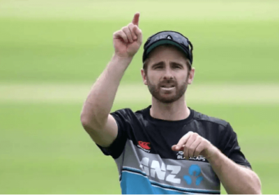 Kane Williamson, in a striped shirt, points his finger up during a match break. Expect New Zealand to miss Williamson in the early India Test series due to a groin strain.