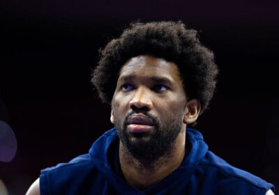 Philadelphia center Joel Embiid, in blue jacket, looks on in file photo. Joel Embiid gets a three-game suspension from the NBA for shoving a columnist after the Philadelphia 76ers match over the weekend.