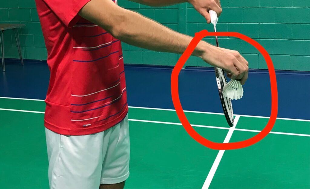 An unidentified shuttler is aiming to serve but part of the image is shaded with a red circle to signify possible service delay based on the BWF. BWF to crack down on delaying service in doubles matches