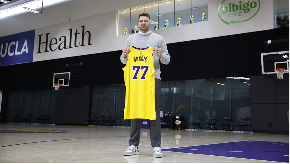 Slovenian guard Luka Doncic poses with his new Lakers No.77 jersey as he arrives at the team's practice facility on Tuesday. Doncic 'excited for new Lakers journey after 'shock' trade