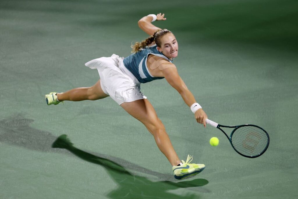 Russia's Mirra Andreeva stretches for a shot as she warms up for the Miami Open 2025. Osaka advances in Miami Open; Andreeva 'stays off social media'