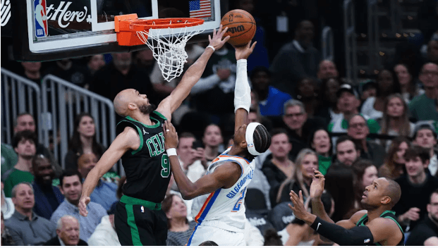 OKC guard Shai Gilgeous-Alexander (left) drives hard for a layup against Boston Celtics guard Derrick White (right) in their game on Wednesday in Boston. Celtics vs Thunder showdown has OKC clinching playoff berth