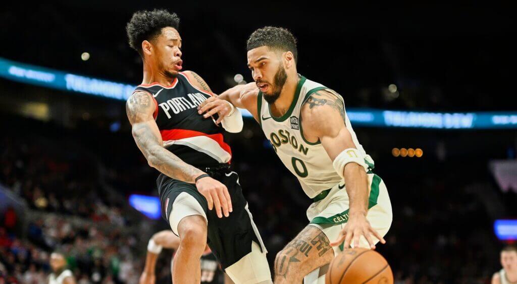 Anfernee Simons (left) defends against Boston forward Jayson Tatum (right) at an NBA regular season game in file photo. The two will become teammates next season but its unsure they will play on the court together due to Tatum's Achilles injury. Anfernee Simons trade merits Boston home run; Holiday to Blazers